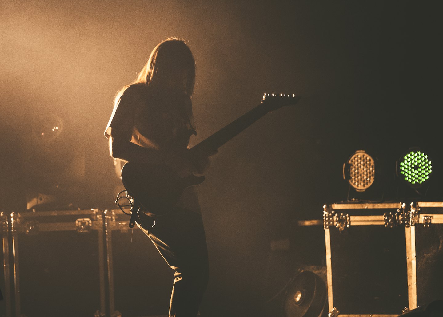 Un musicista con i capelli lunghi suona la chitarra elettrica sul palco.