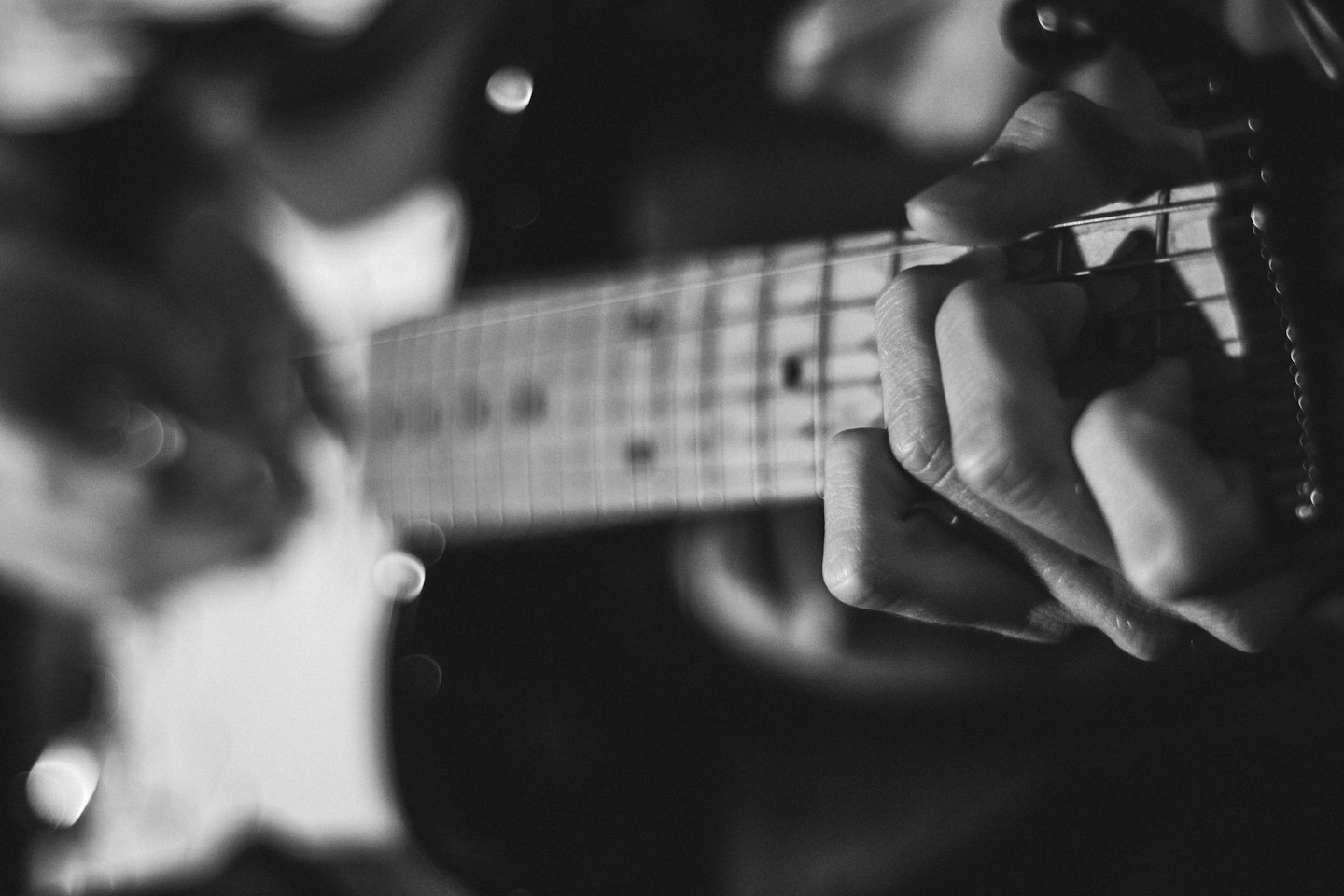 Mani che suonano la tastiera e il corpo di una chitarra elettrica.